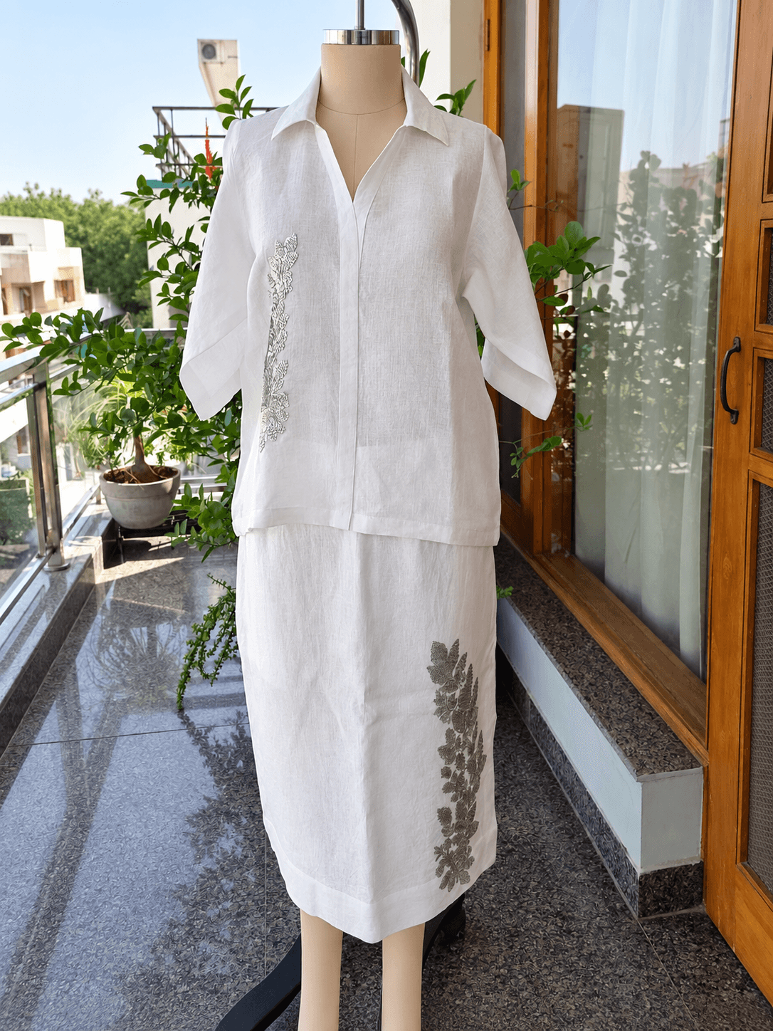 White embroidered linen outfit displayed on a dress form